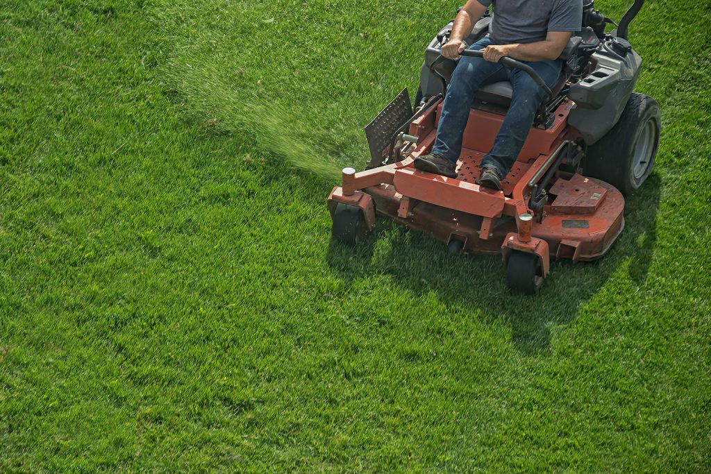 closeup of a riding landscaper on the lawn mower cutting the grass
